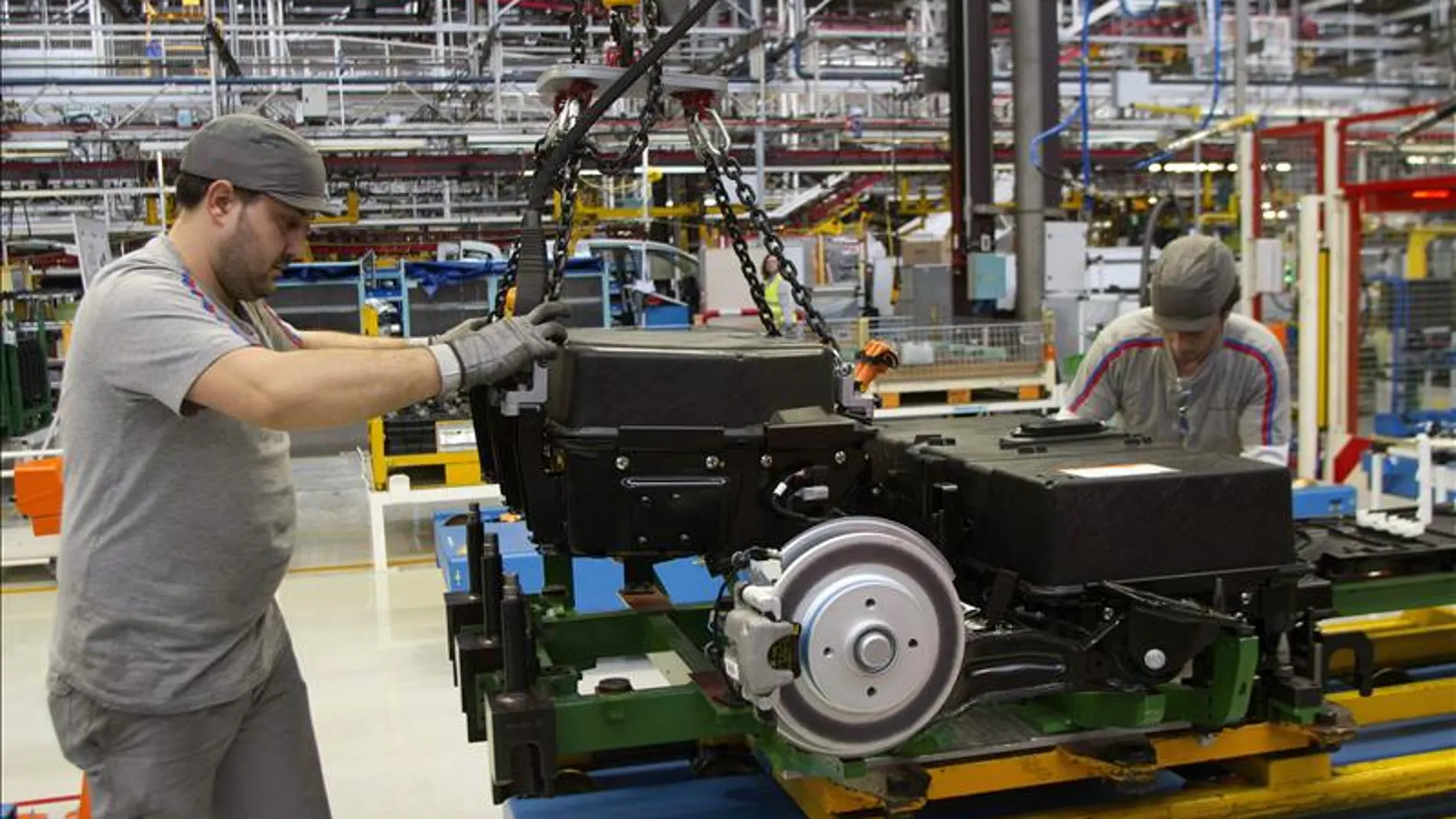 Dos operarios colocan baterías en un automóvil Dos operarios colocan baterías en un automóvil