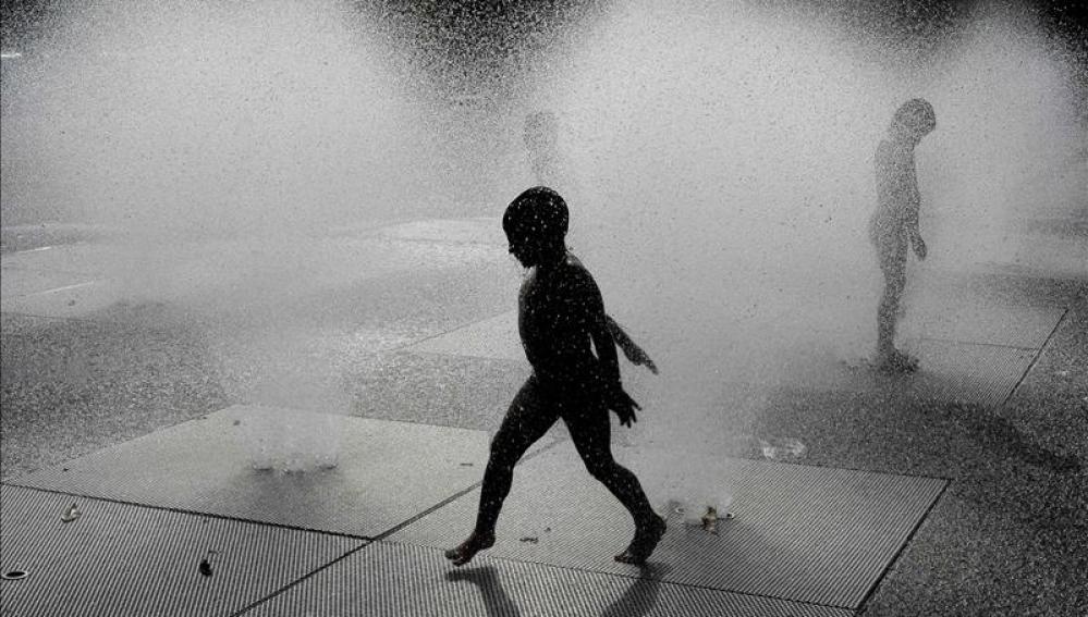 Un niño se refresca en una fuente
