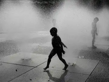 Un niño se refresca en una fuente Un niño se refresca en una fuente