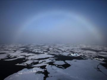 El arco iris apareciendo en el horizonte en el Ártico