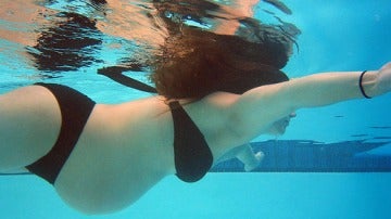 Mujer embarazada nadando en la piscina