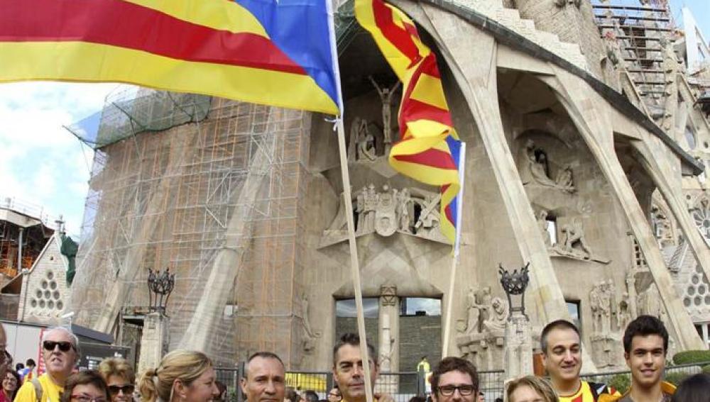 Varias personas congregadas frente a la Sagrada Familia participan en la cadena humana 