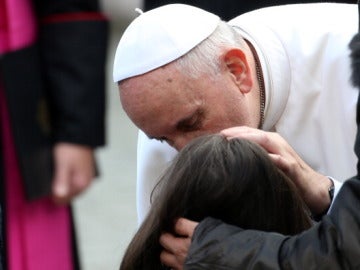 El Papa besa a una los visitantes