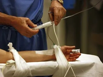 Un sanitario administra fármacos a un paciente. Un sanitario administra fármacos a un paciente.