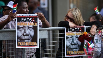 Dos ciudadanos sudafricanos esperan el paso del cortejo de Nelson Mandela en Pretoria