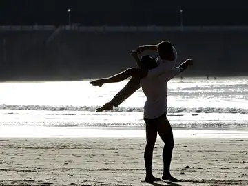 Dos jóvenes disfrutan del atardecer en la playa de La Concha de San Sebastián Dos jóvenes disfrutan del atardecer en la playa de La Concha de San Sebastián