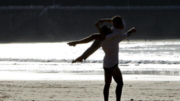  Dos jóvenes disfrutan del atardecer en la playa de La Concha de San Sebastián