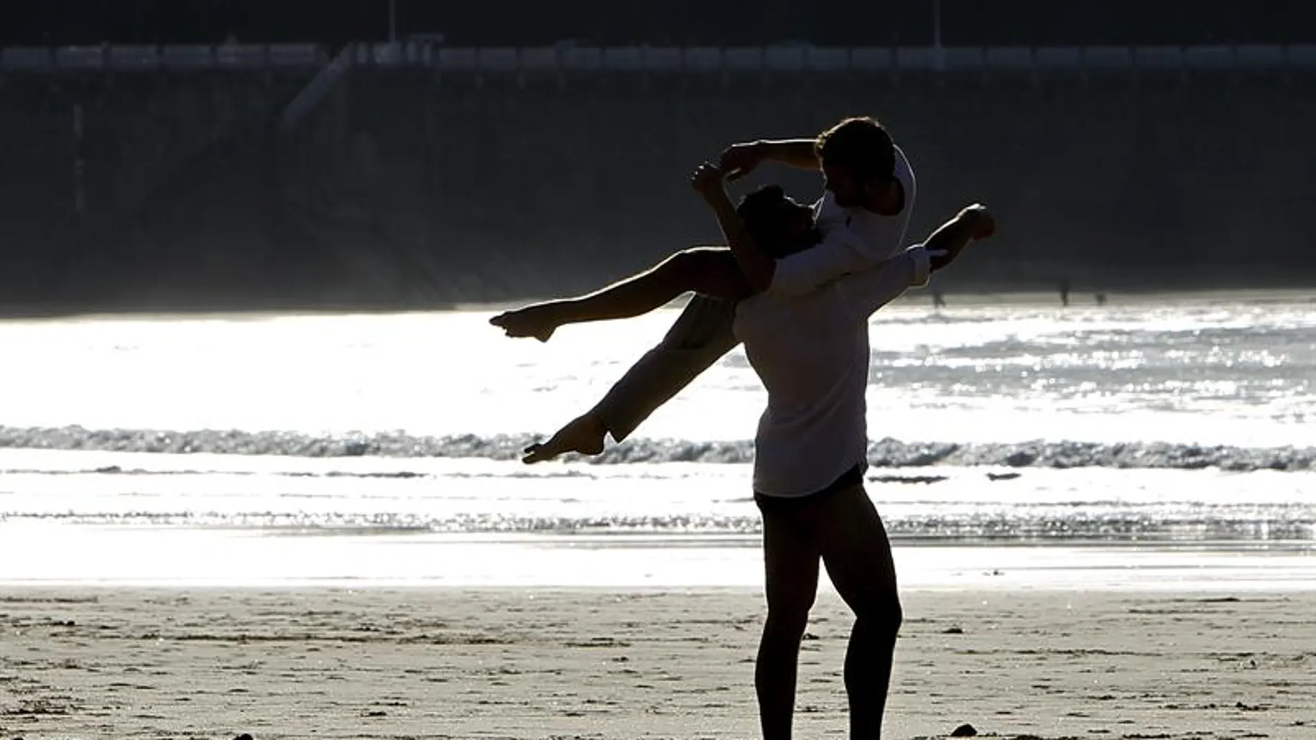 Dos jóvenes disfrutan del atardecer en la playa de La Concha de San Sebastián Dos jóvenes disfrutan del atardecer en la playa de La Concha de San Sebastián