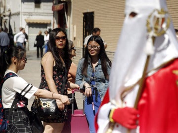 Turistas viendo un paso de Semana Santa
