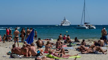 Playa de Ibiza llena de personas tomando el sol