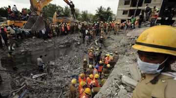Miembros de los equipos de rescate buscan víctimas en el lugar del edificio derrumbado