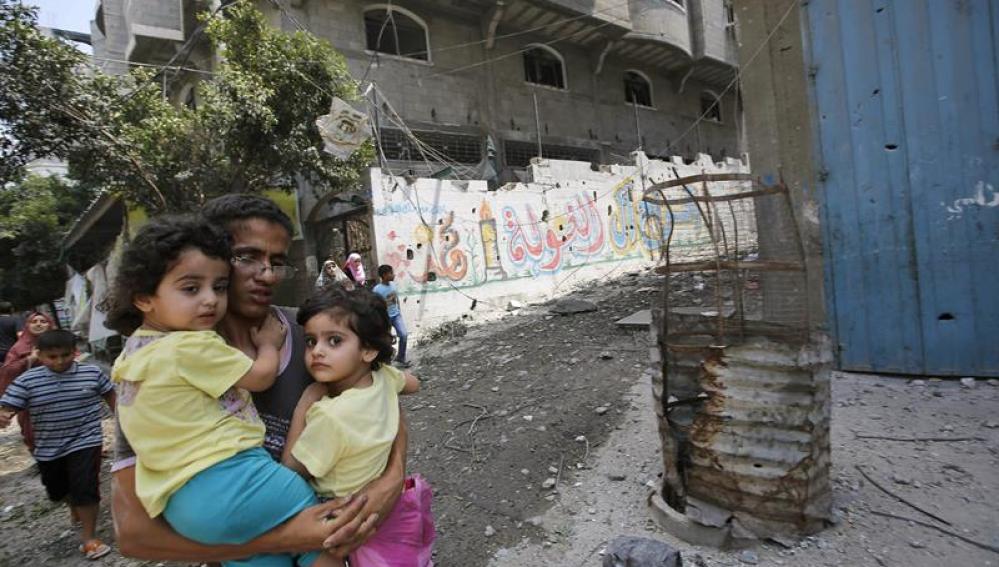 Un padre huye junto a sus hijos durante un bombardeo en Gaza