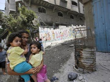 Un padre huye junto a sus hijos durante un bombardeo en Gaza