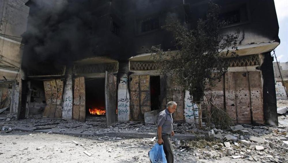 Un palestino abandona su casa en llamas