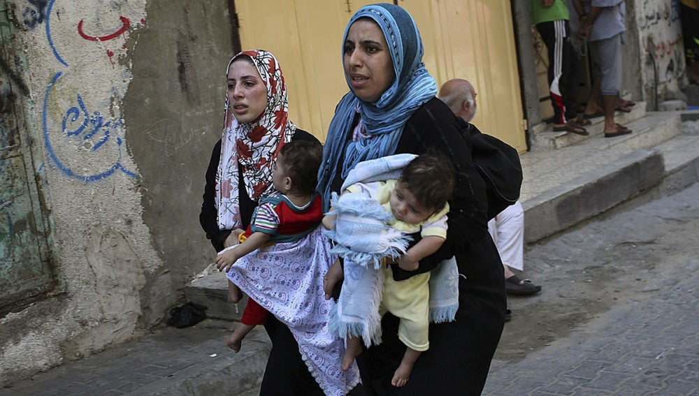 Dos mujeres llevan a sus hijos en brazos