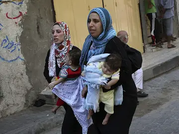Dos mujeres llevan a sus hijos en brazos Dos mujeres llevan a sus hijos en brazos