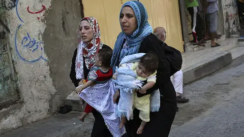 Dos mujeres llevan a sus hijos en brazos Dos mujeres llevan a sus hijos en brazos