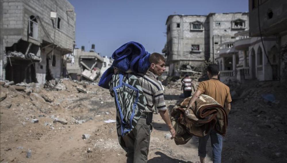 Ciudadanos palestinos caminando sobre ruinas