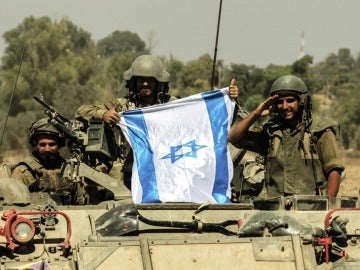 Soldados israelís portan una bandera de Israel sobre un tanque