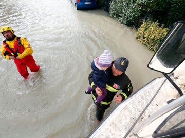 Bomberos rescatan a una niña durante las inundaciones en Italia