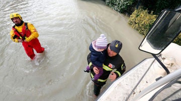 Bomberos rescatan a una niña durante las inundaciones en Italia