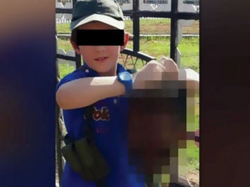 Un niño sujeta la cabeza de un soldado