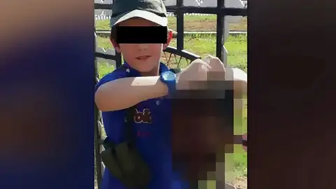 Un niño sujeta la cabeza de un soldado Un niño sujeta la cabeza de un soldado