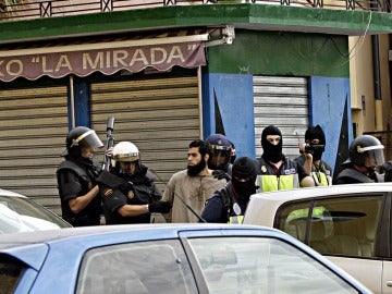 Agentes de policía junto a uno de los detenidos