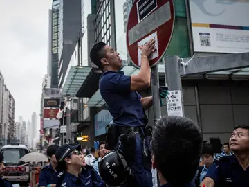 Un policía quita un cartel de los manifestantes en Hong Kong Un policía quita un cartel de los manifestantes en Hong Kong