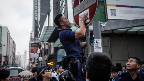 Un polic&iacute;a quita un cartel de los manifestantes en Hong Kong