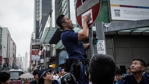 Un policía quita un cartel de los manifestantes en Hong Kong Un policía quita un cartel de los manifestantes en Hong Kong