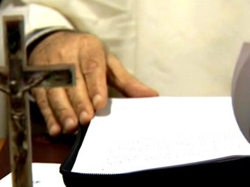 Un religioso con documentos y un crucifijo