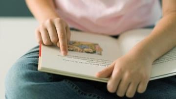 Una niña lee un libro de texto.