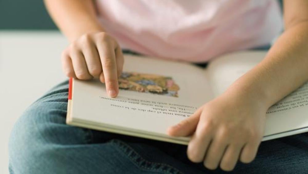 Una niña lee un libro de texto.