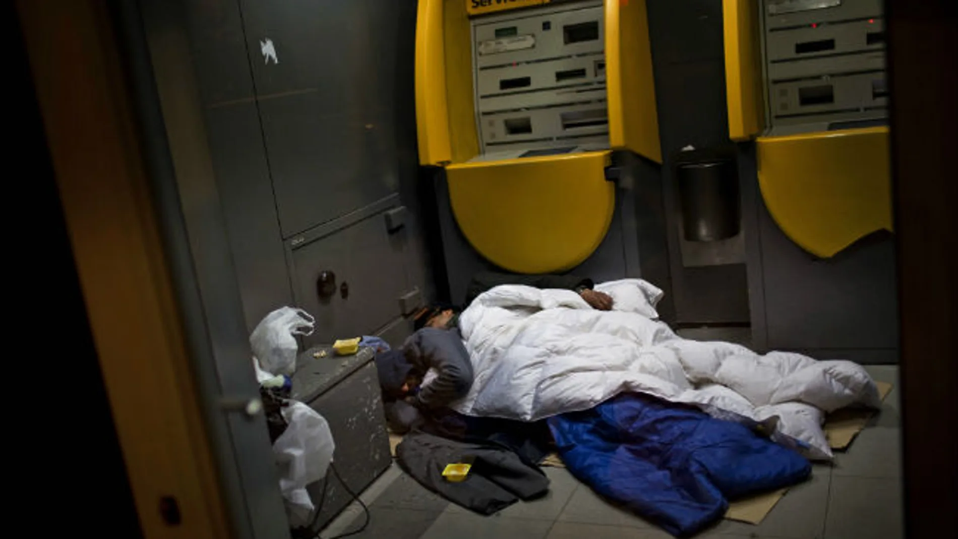 Dos vagabundos duermen en un cajero en Barcelona. Dos vagabundos duermen en un cajero en Barcelona.