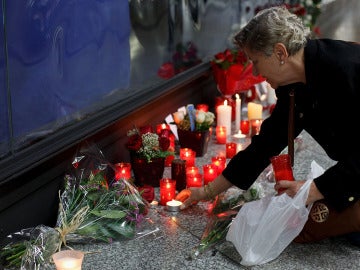 Una mujer enciende una vela en el monumento a las víctimas en Atocha