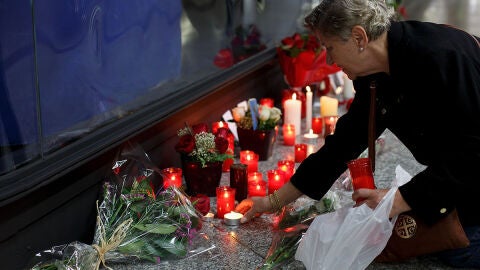 Una mujer enciende una vela en el monumento a las v&iacute;ctimas en Atocha