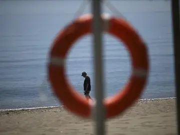 Un turista pasea por la orilla del mar en una playa Un turista pasea por la orilla del mar en una playa