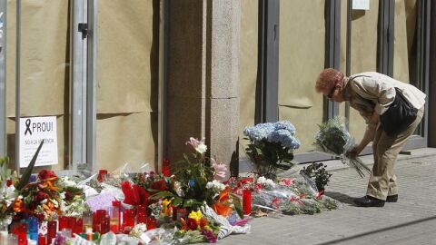 Una mujer deposita flores en el instituto Joan Fuster.