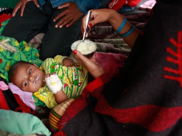 Un bebé es alimentado por su madre en un campamento de afectados en Nepal.