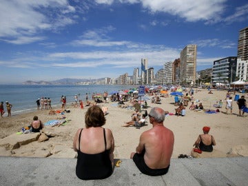 Varios turistas disfrutan de sus vacaciones en la playa.