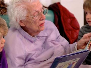Una anciana leyéndole un cuento a dos niños