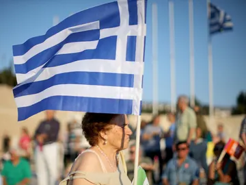 Una mujer porta una bandera de Grecia Una mujer porta una bandera de Grecia