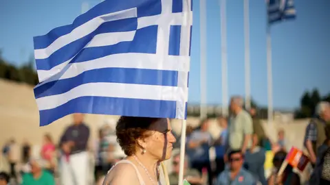 Una mujer porta una bandera de Grecia Una mujer porta una bandera de Grecia