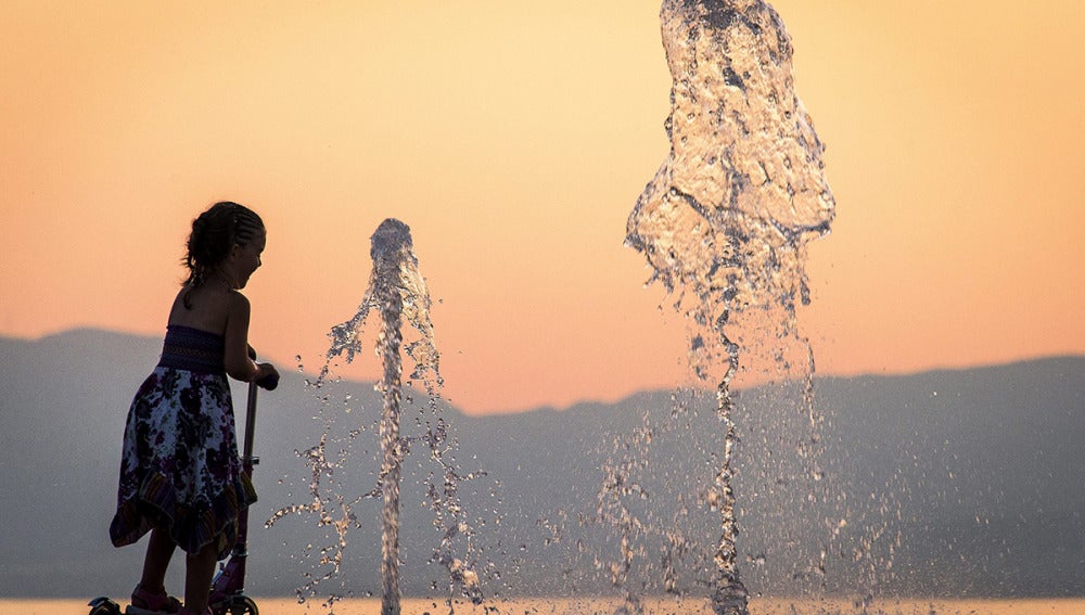 Una niña se refresca en una fuente para combatir el calor en Francia