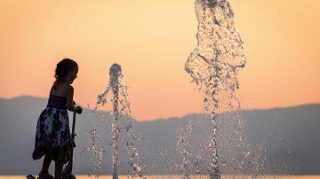 Una niña se refresca en una fuente para combatir el calor en Francia