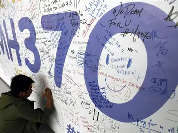 Un hombre escribiendo mensajes en honor a las víctimas del vuelo MH370 de Malaysia Airlines Un hombre escribiendo mensajes en honor a las víctimas del vuelo MH370 de Malaysia Airlines
