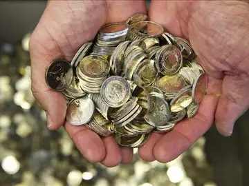 Un hombre sostiene varias monedas de euro Un hombre sostiene varias monedas de euro