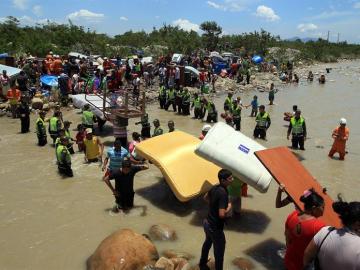 Cientos de colombianos cargan sus pertenencias por el río Táchira