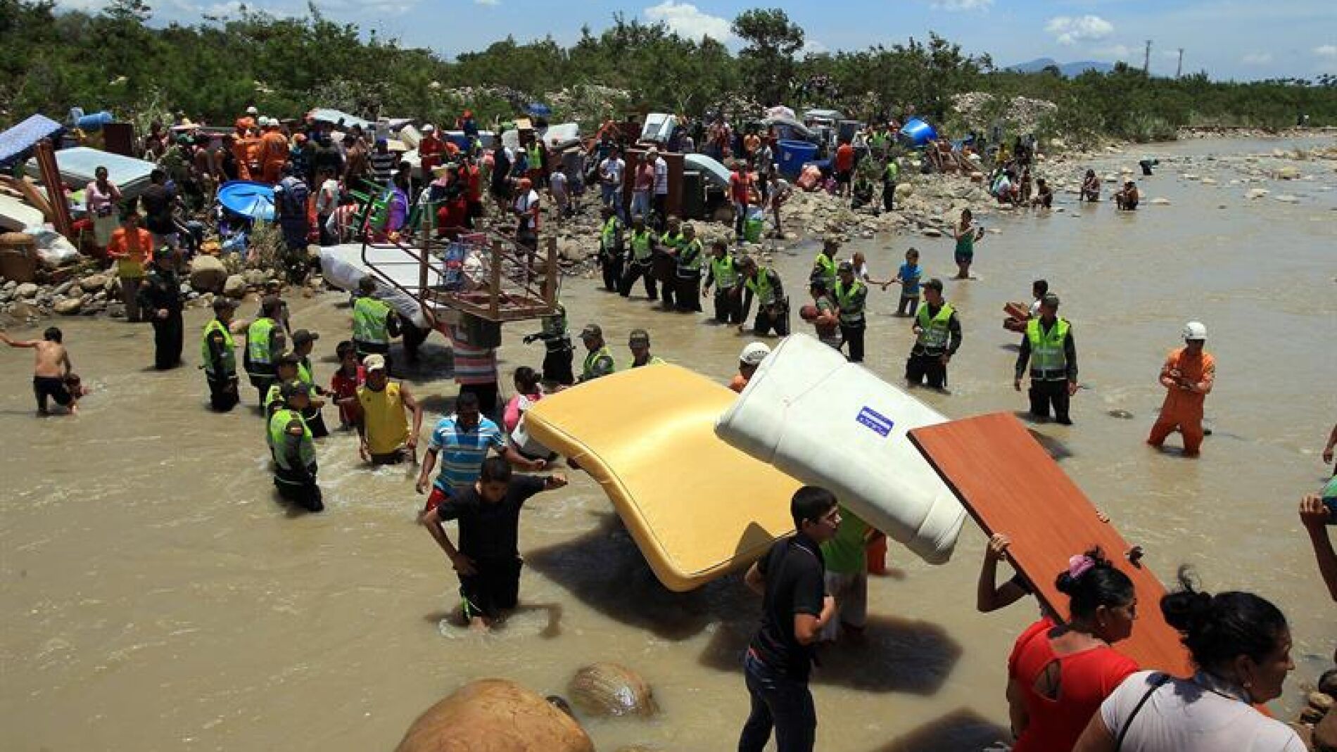 Cientos de colombianos cargan sus pertenencias por el r&iacute;o T&aacute;chira